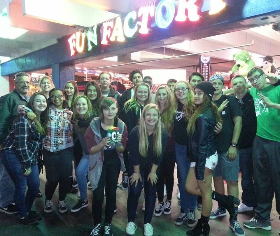 A group of teens poses in front of a 