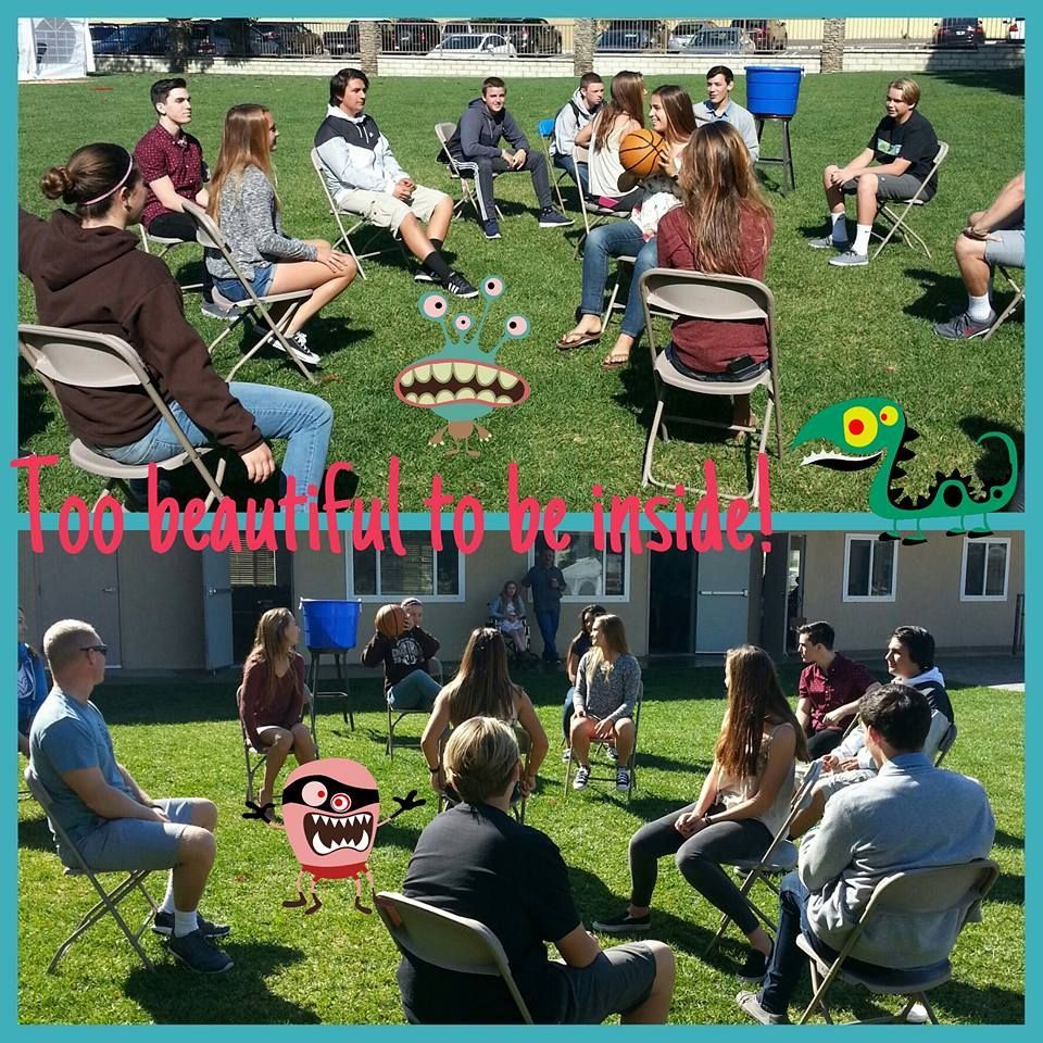 People in a circle outdoors, sitting in chairs. Monsters added. Text: 