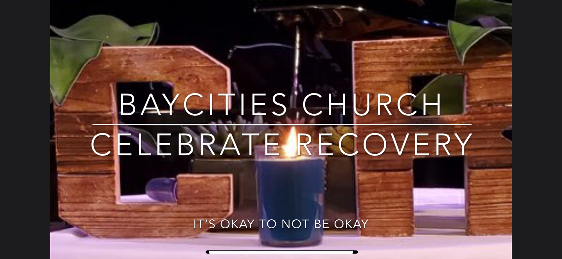 Wooden letters spell “G-R” with a lit candle, text: “Bay Cities Church Celebrate Recovery.” and “It’s okay to not be okay.”