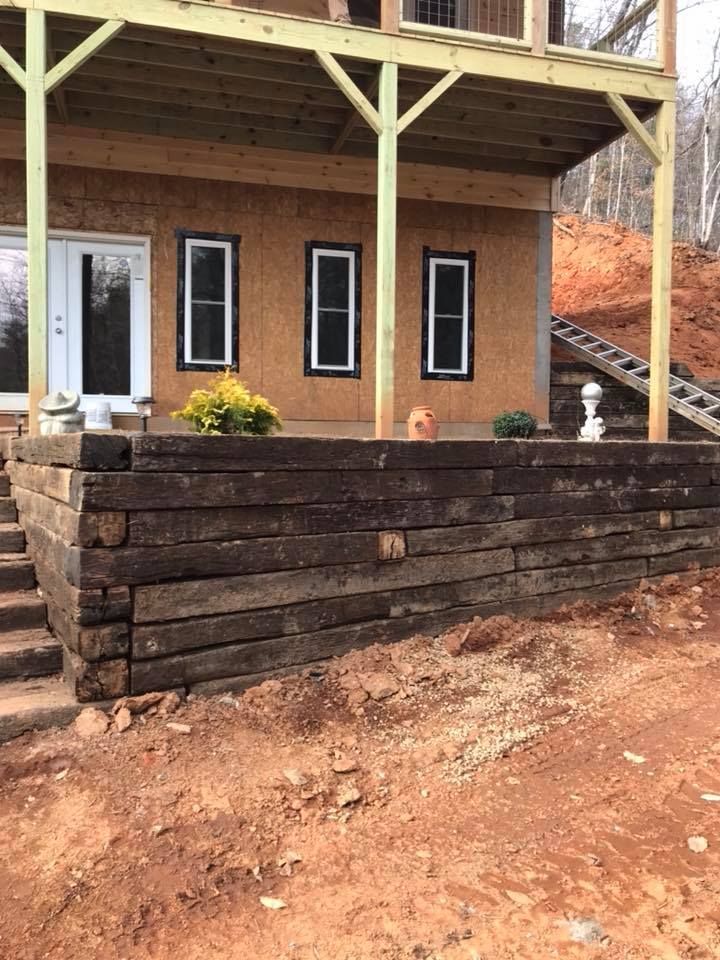 A house under construction with a wooden retaining wall in front of it.
