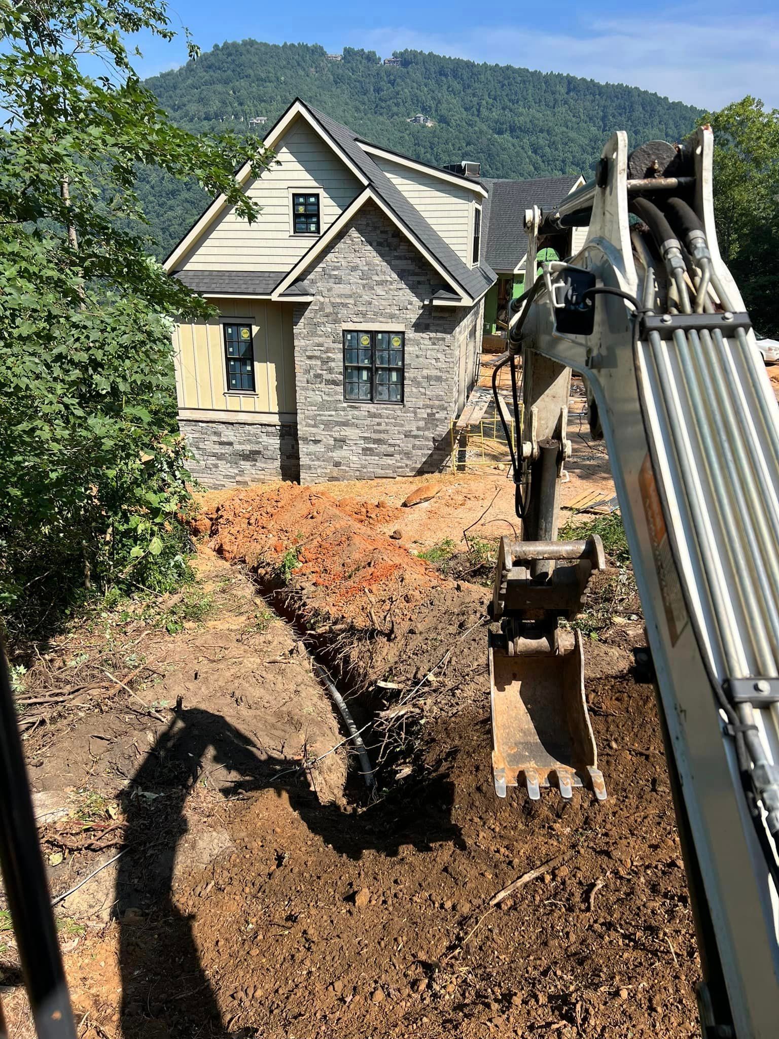 A large excavator is digging a hole in front of a house.