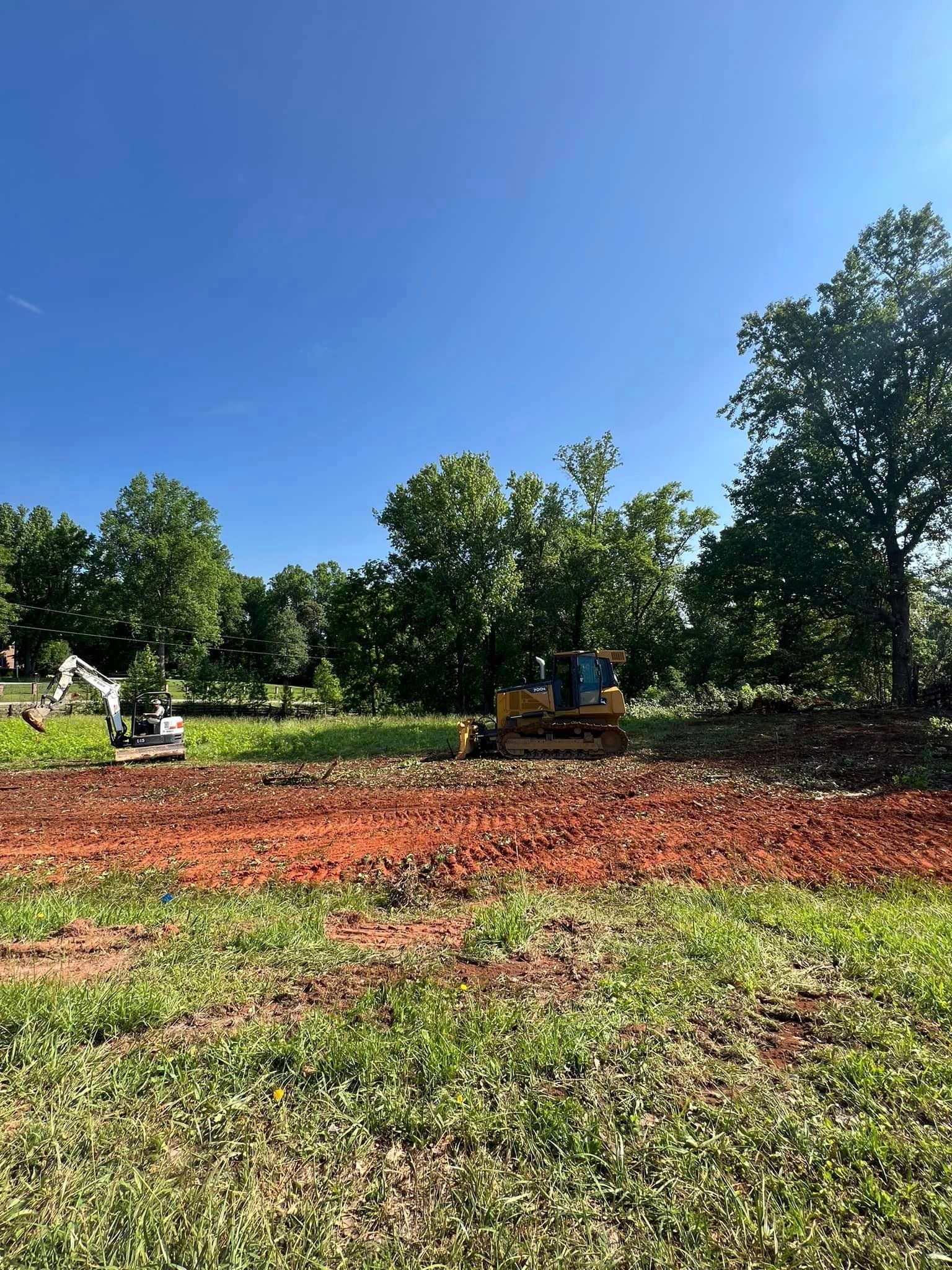 A bulldozer is moving dirt in a field with trees in the background.