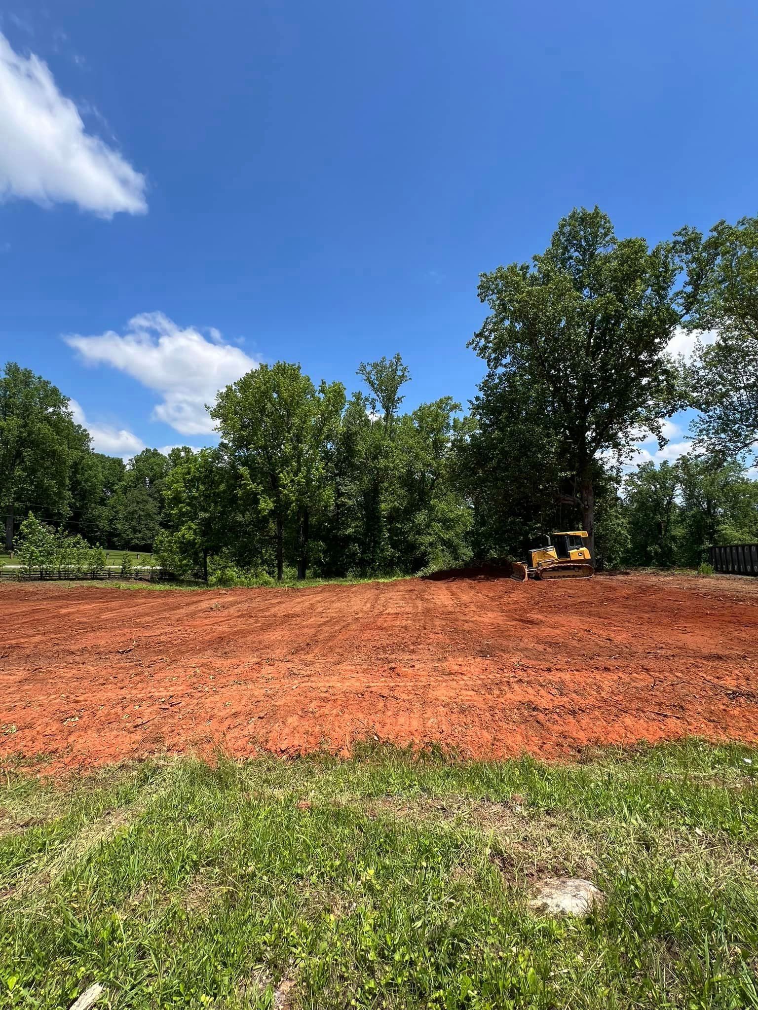 A large dirt field with trees in the background on a sunny day.