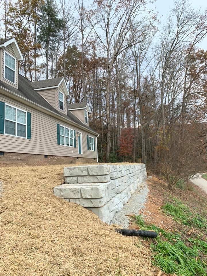 A house is sitting on top of a hill next to a stone wall.
