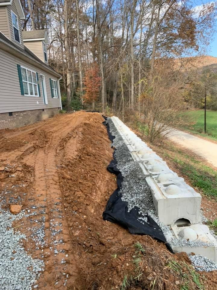 A house is being built on a hill next to a dirt road.