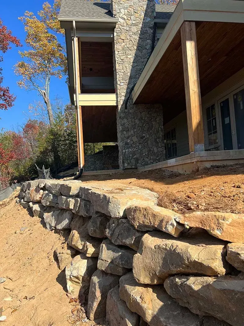 A stone wall is being built in front of a house.