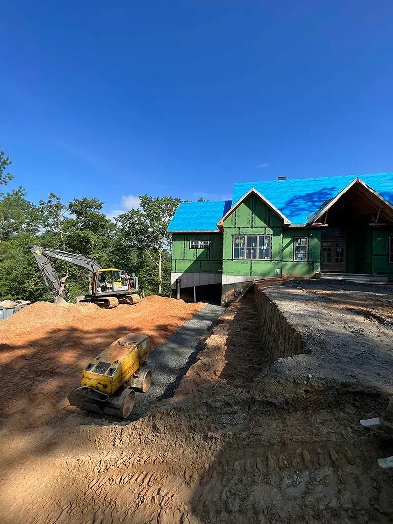A house is being built with a blue roof and a large pile of dirt in front of it.