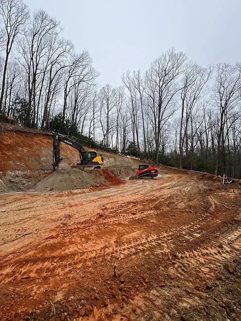 A bulldozer is driving down a dirt road in the middle of a forest.