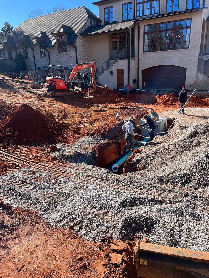 A construction site with a large house in the background and a lot of dirt.
