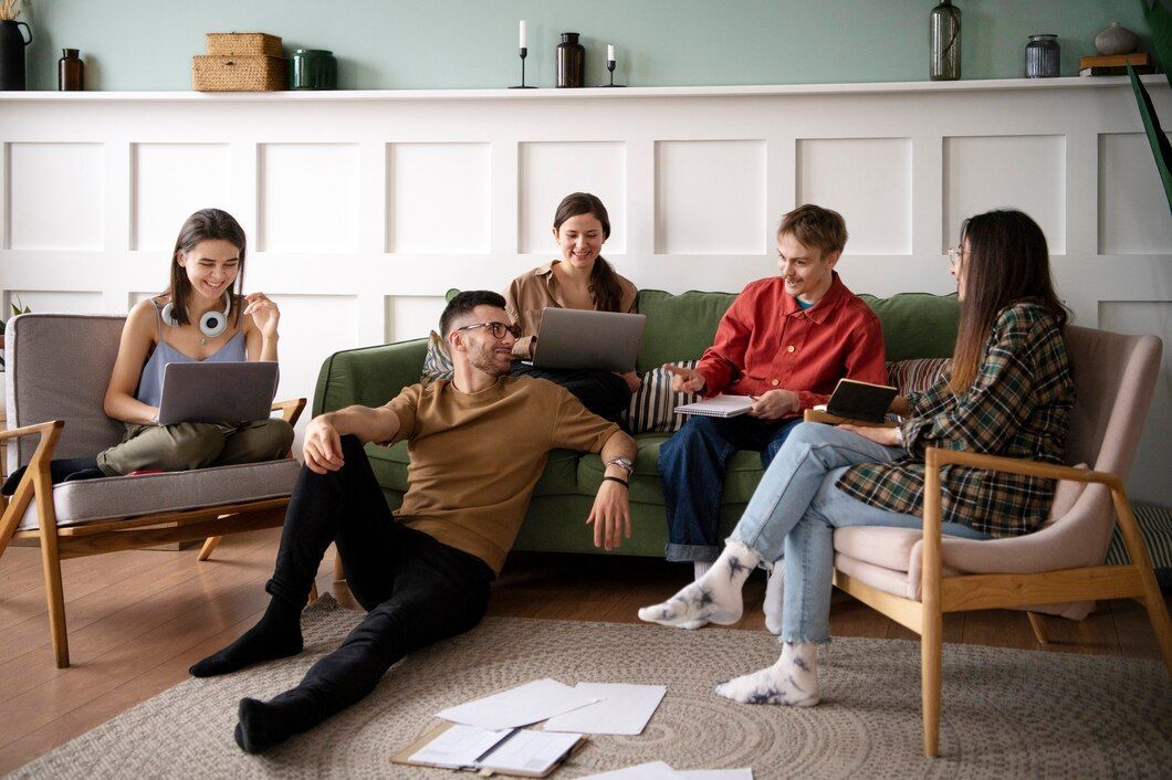 A group of people are sitting on a couch using laptops.