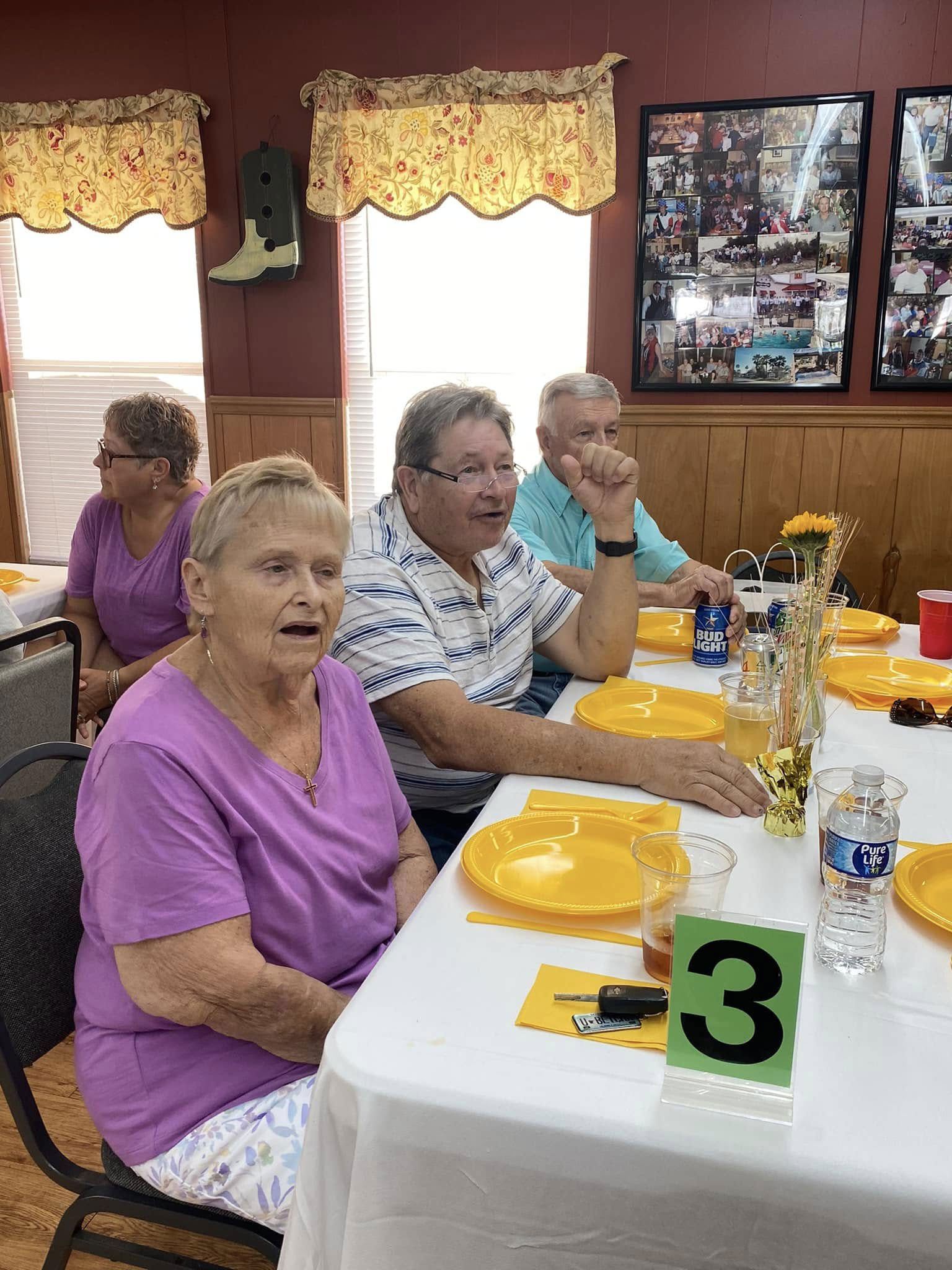 People seated at a table in a dining room, with yellow plates and a table number 3 sign.