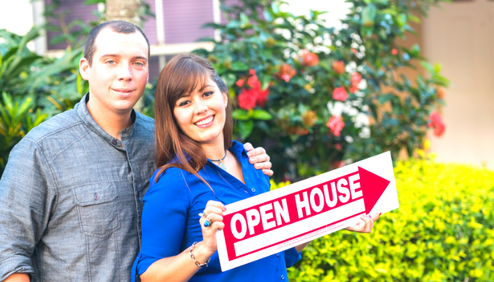 A Man and A Woman Are Holding an Open House Sign — Ocala, FL — Invictus Real Estate, LLC