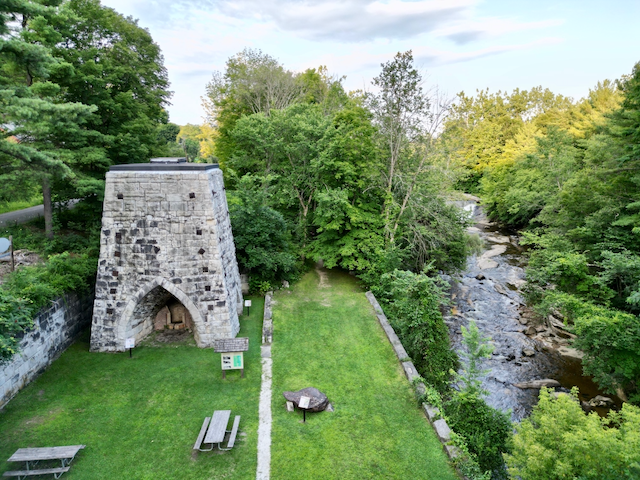 An aerial view of a picnic area next to a river surrounded by trees.