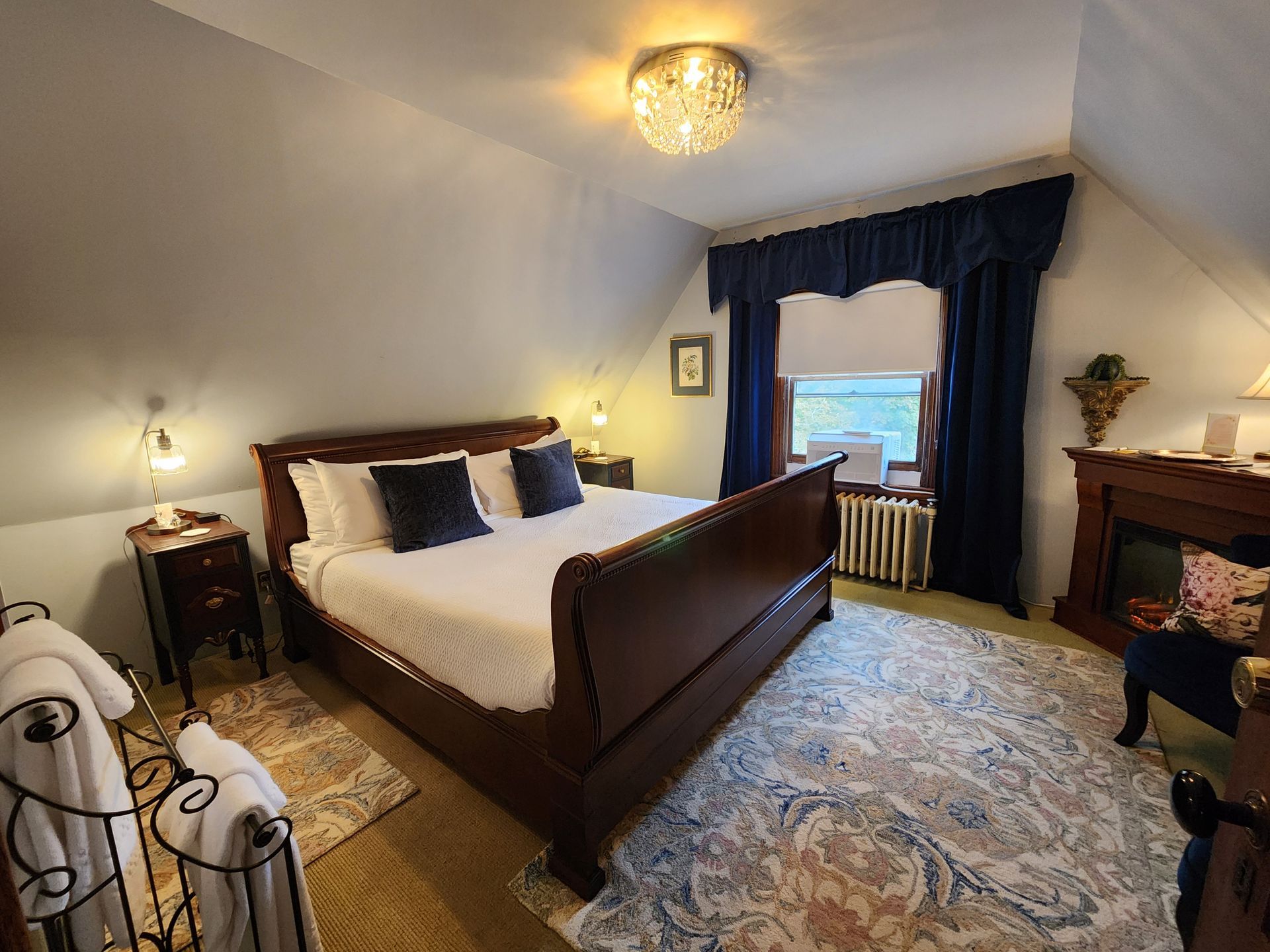 Bedroom with a bed, fireplace, blue curtains, and rug.