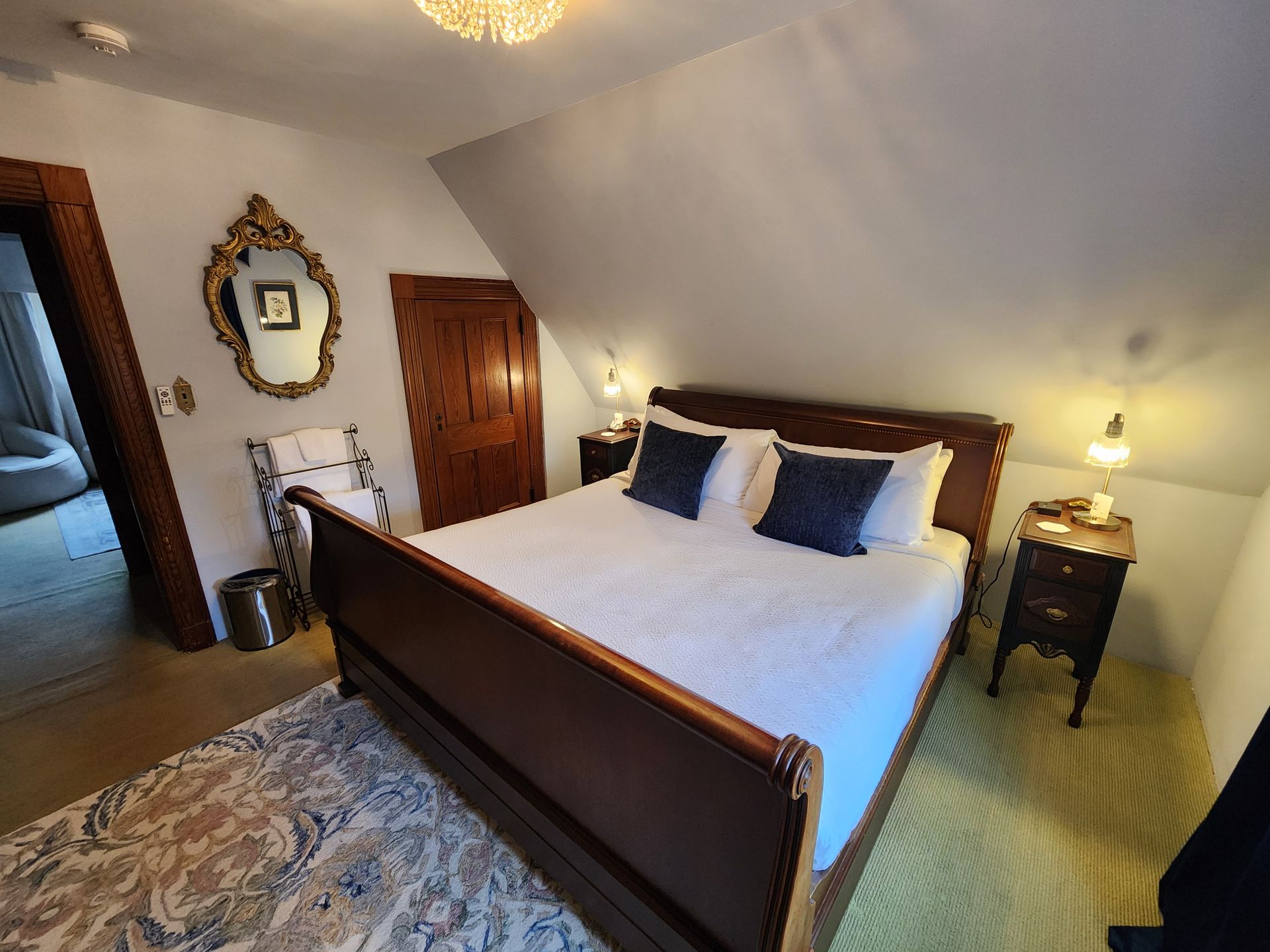 Bedroom with a sleigh bed, nightstands, mirror, and patterned rug.