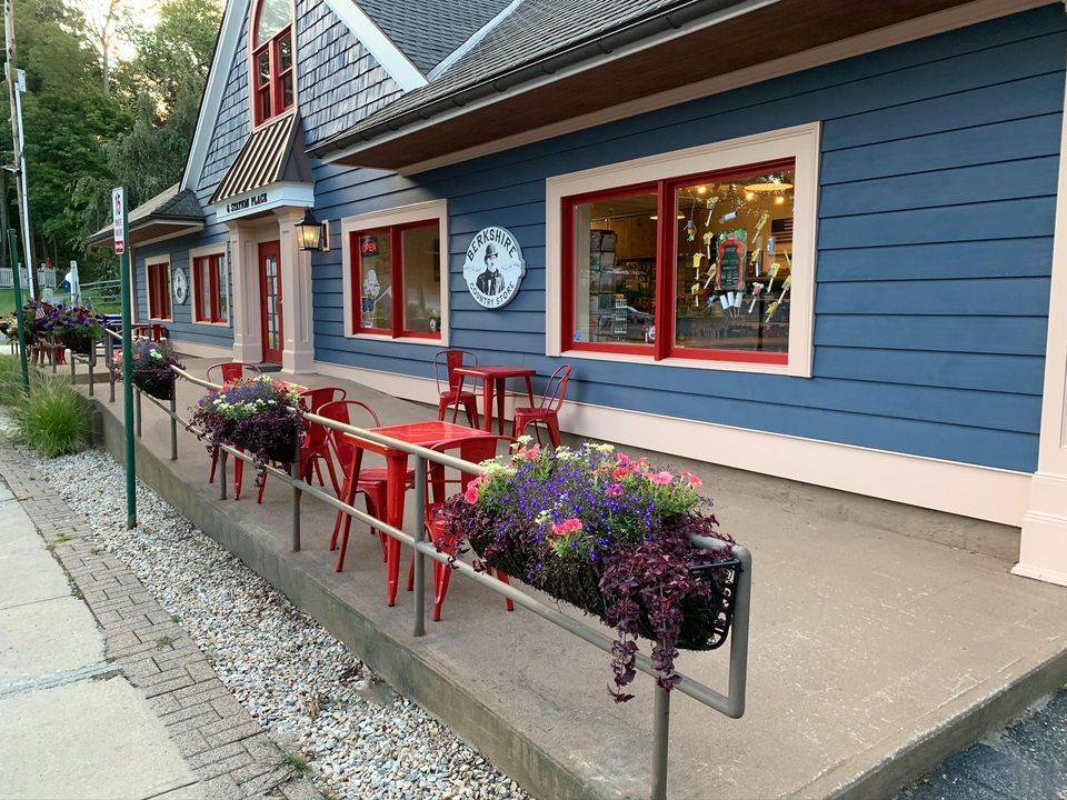 A blue building with red tables and chairs in front of it