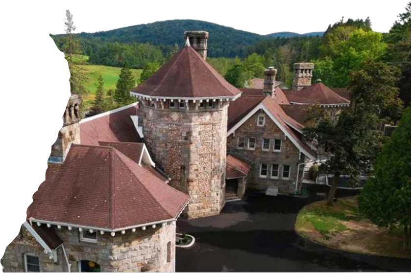 An aerial view of a large stone castle with mountains in the background