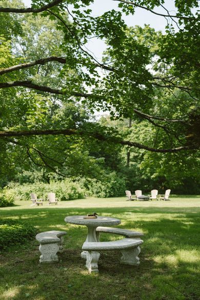 A picnic table and benches in the middle of a lush green expansive lawn.
