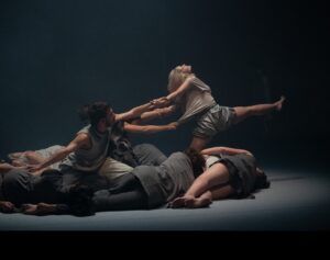 A group of people are dancing on a stage in a dark room.