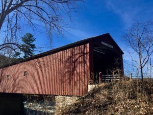 A red covered bridge with a blue sky in the background.