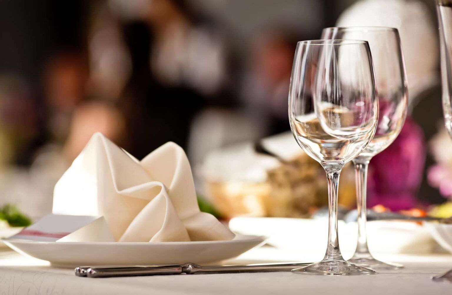 A white plate with a napkin and wine glasses on a table.