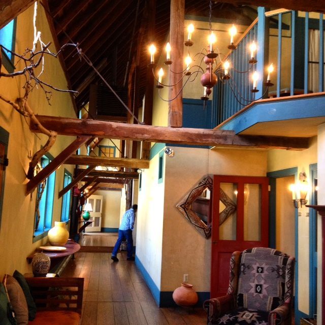 A man walking down a hallway with a chandelier hanging from the ceiling