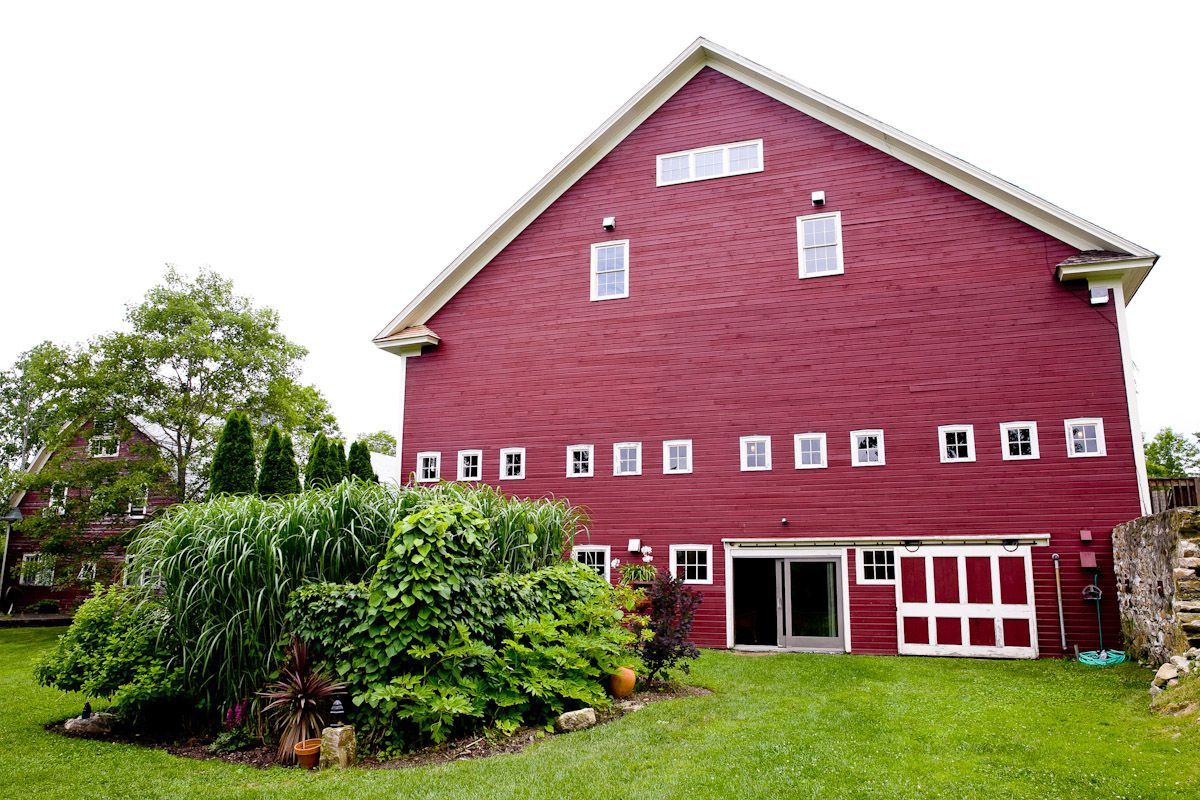 A large red barn is sitting in the middle of a lush green field.