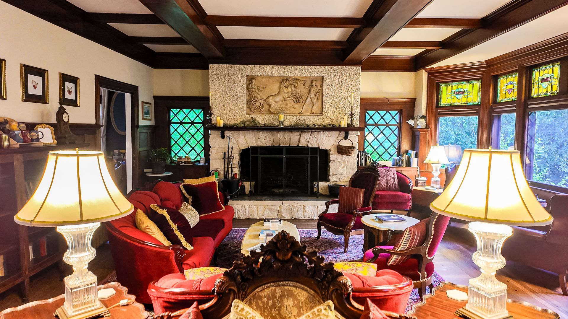 Living room with stone fireplace, red furniture, and stained-glass windows.