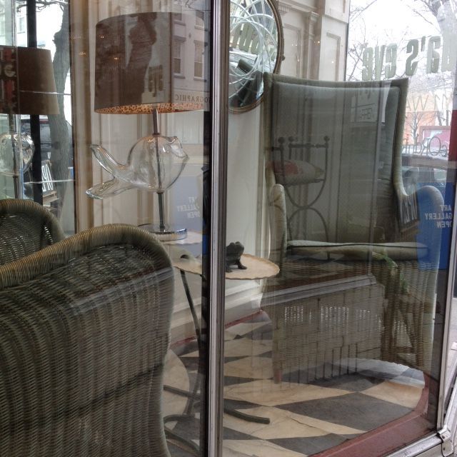 A wicker chair is reflected in a glass door