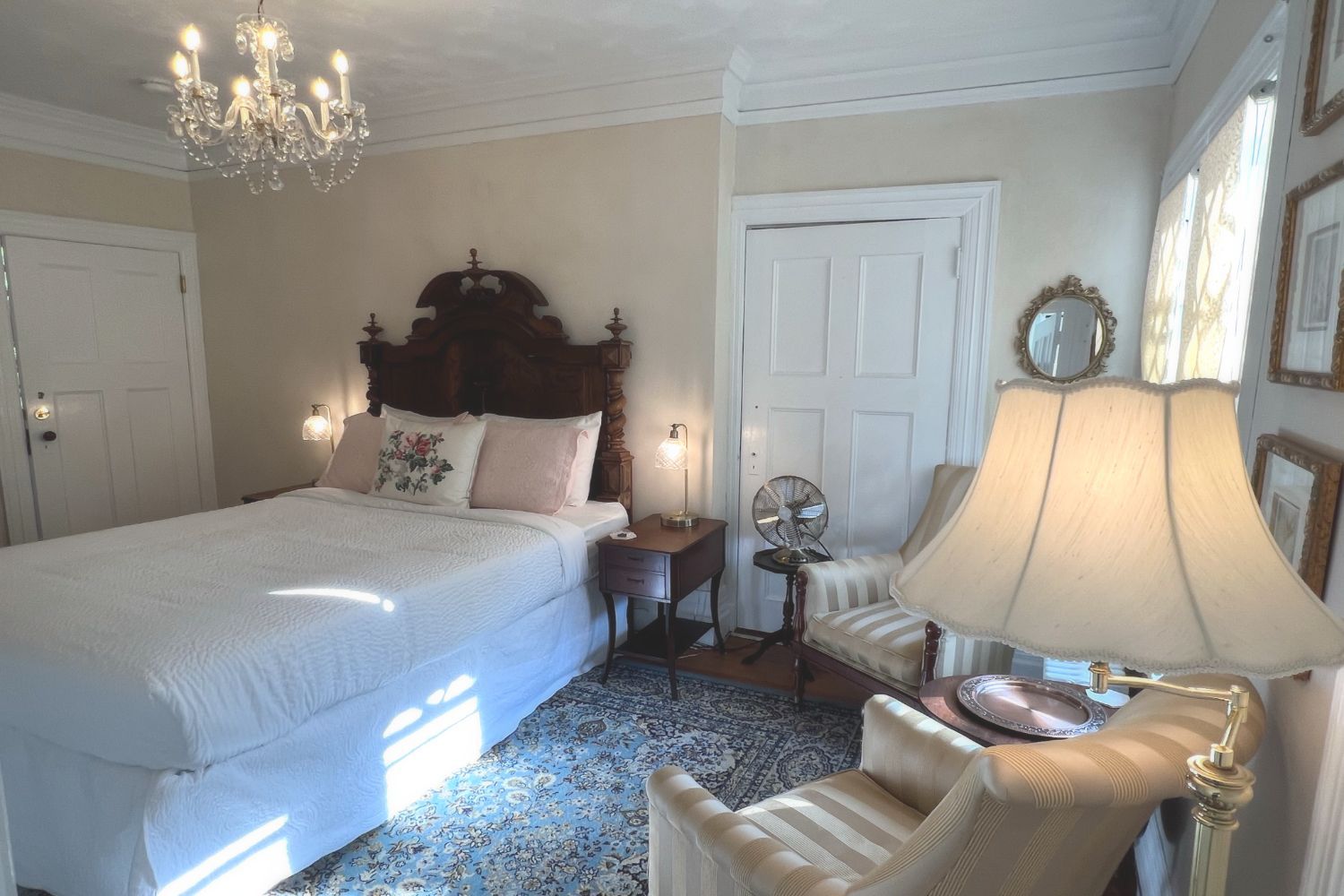 A romantic Victorian bedroom at a New England Country Inn with a bed, chair, lamp, and mirror.