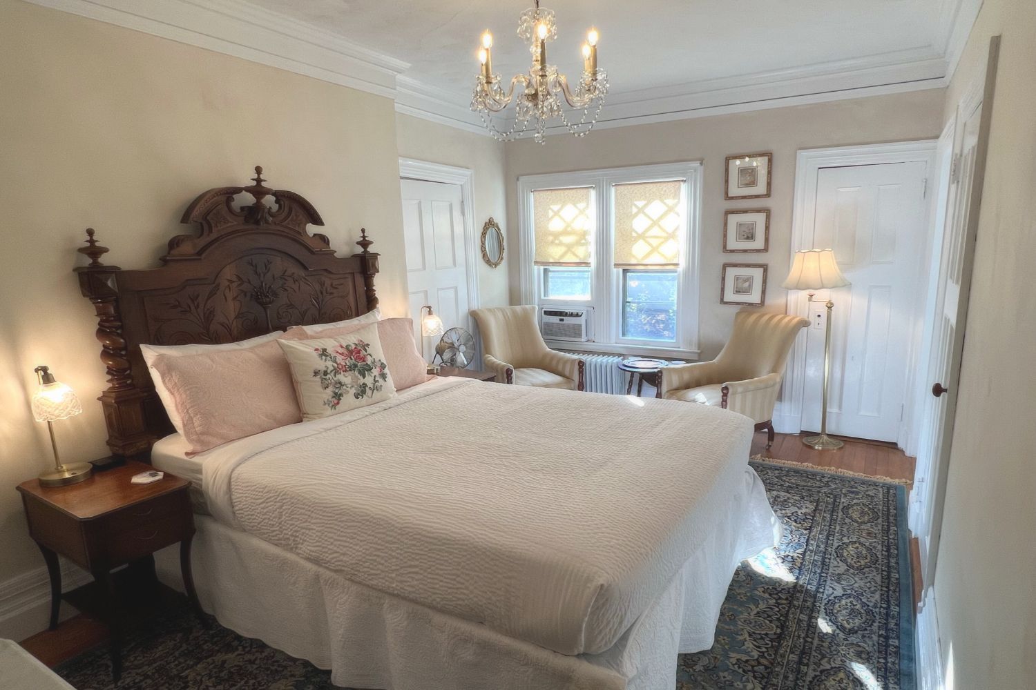 A romantic Victorian bedroom at a New England Country Inn with a bed, chair, lamp, and antique chandelier.