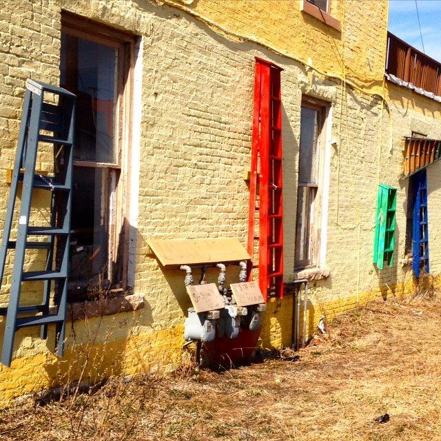 A yellow brick building with a blue ladder on the side