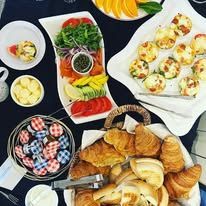 A breakfast display with croissants, smoked salmon, petite egg bites and jams on a table