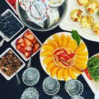 A breakfast display with yogurt, parfait toppings, and fresh fruit on a table