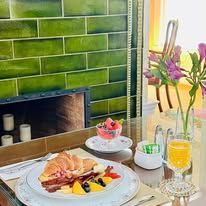 A plate of breakfast food on the table with fresh flowers in front of a fireplace.