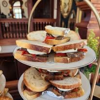 Three plates of sandwiches on a tiered display stand.