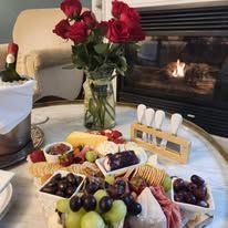 A table topped with a variety of food and flowers in front of a fireplace.
