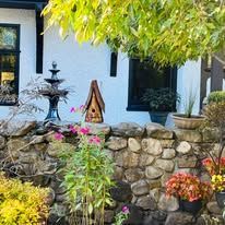 There is a birdhouse in the middle of the garden in front of the house.