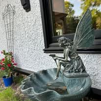 A statue of a fairy sitting on top of a fountain.