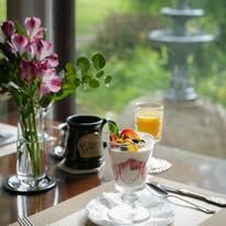 A table with a vase of flowers and a bowl of fruit on it.