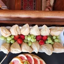 A plate of food with fruit and scones on a table.