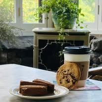 A cup of coffee and a plate of cookies are on a table.