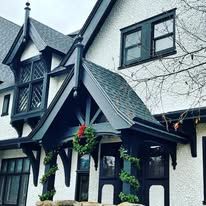 A white and black house with a porch decorated for christmas.
