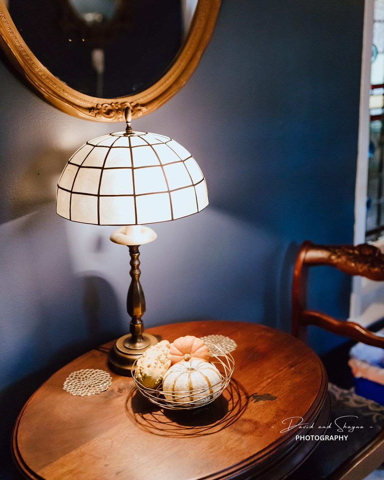 A lamp is sitting on a wooden table next to a mirror.
