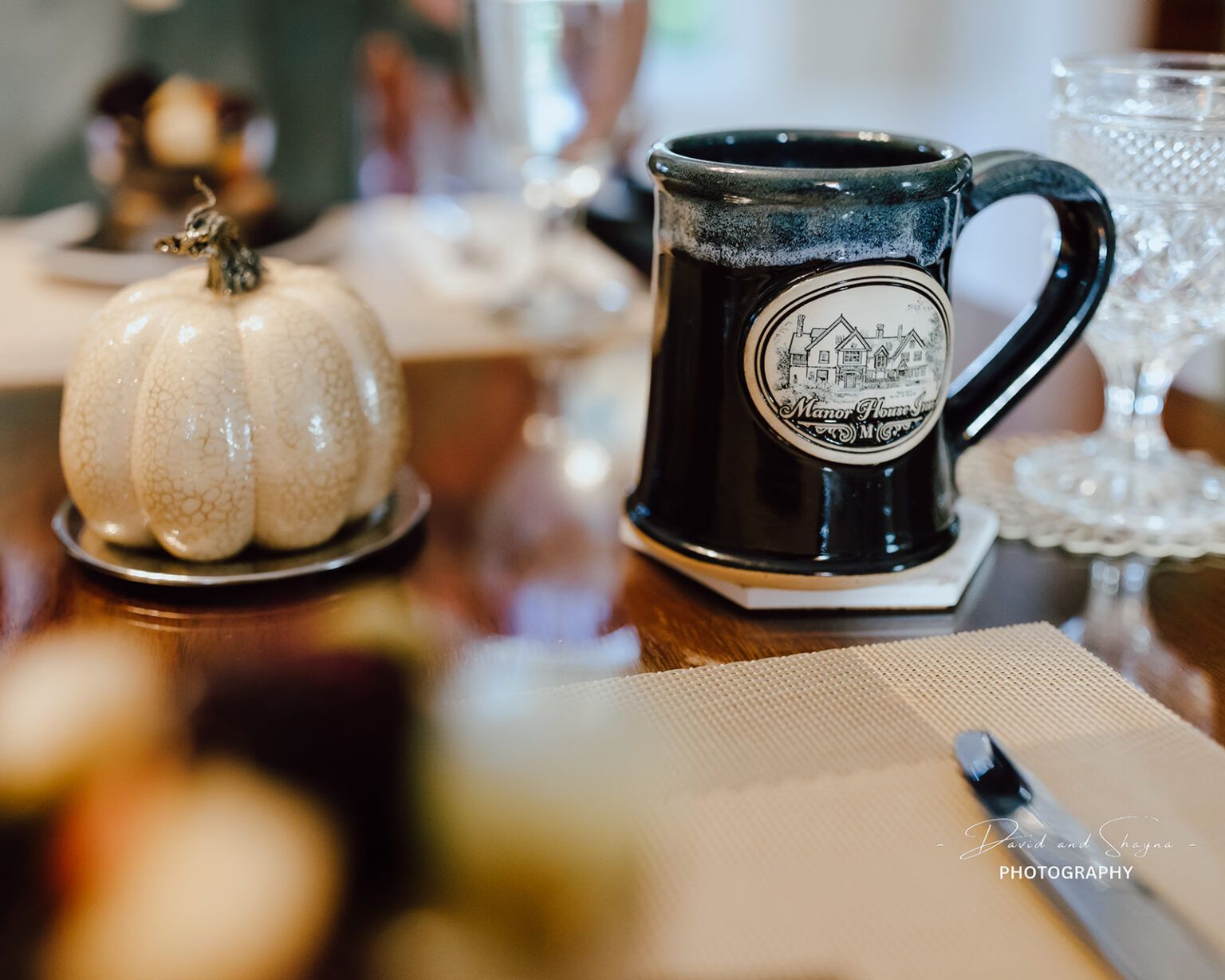 A coffee mug is sitting on a table next to a pumpkin.