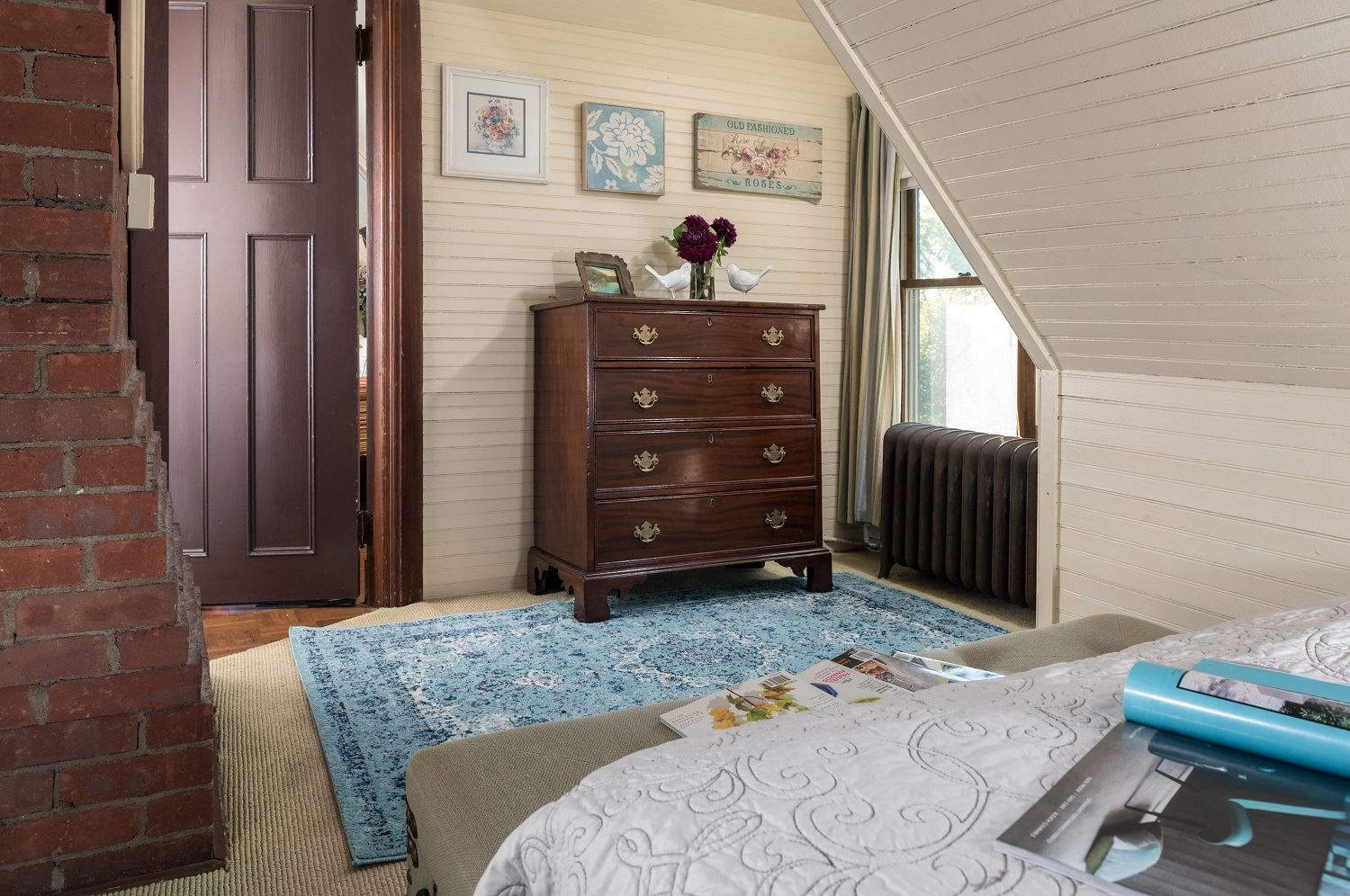 A bedroom with a dresser and a rug on the floor