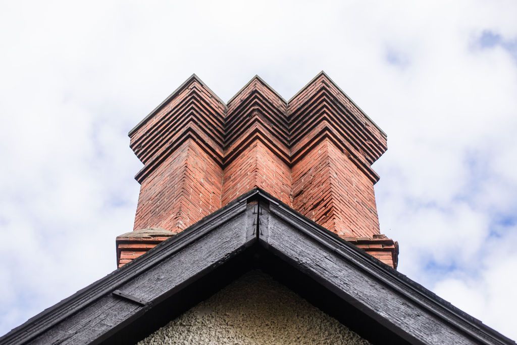 A brick chimney on top of a building with a cloudy sky in the background