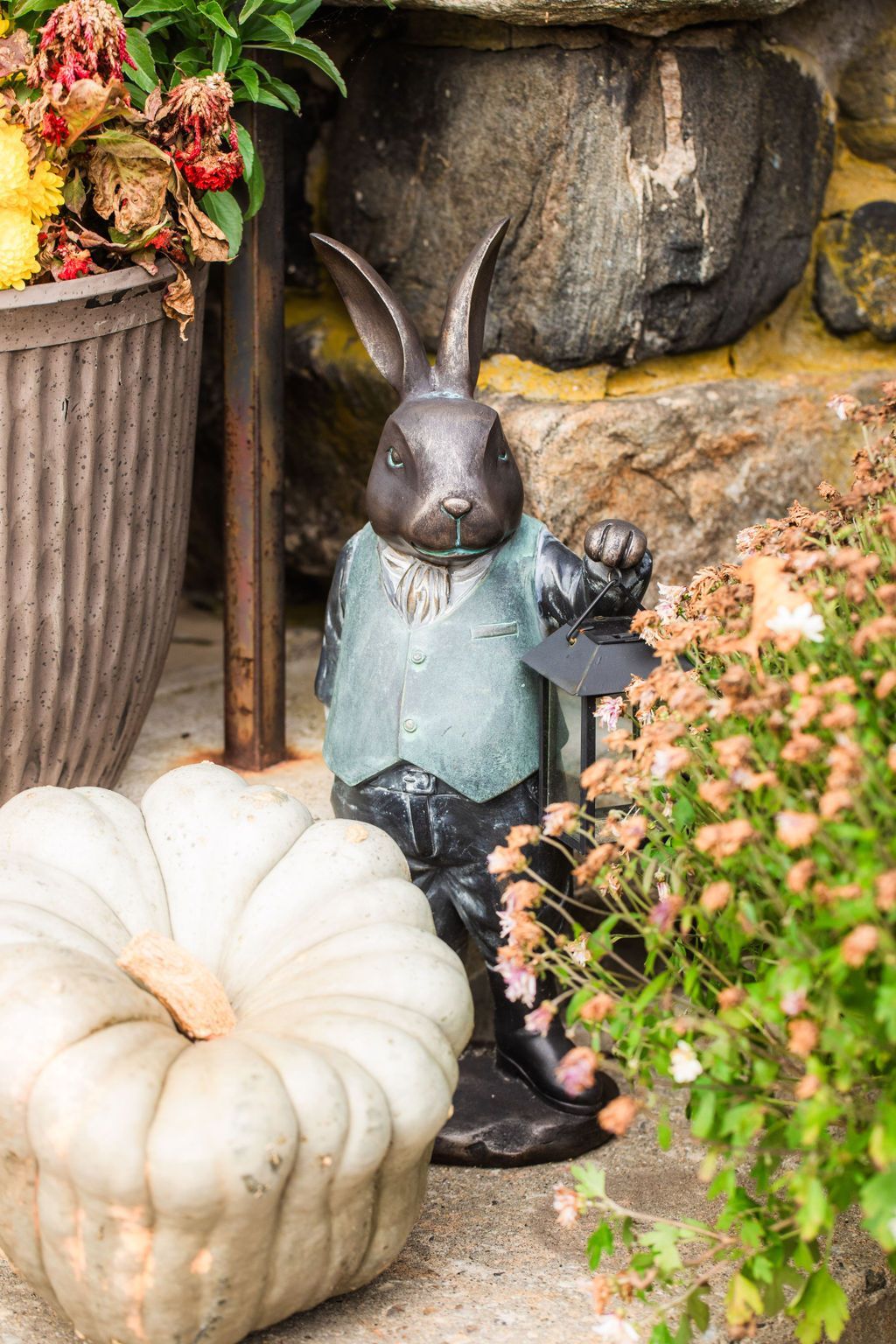 A statue of a rabbit holding a lantern next to a pumpkin.