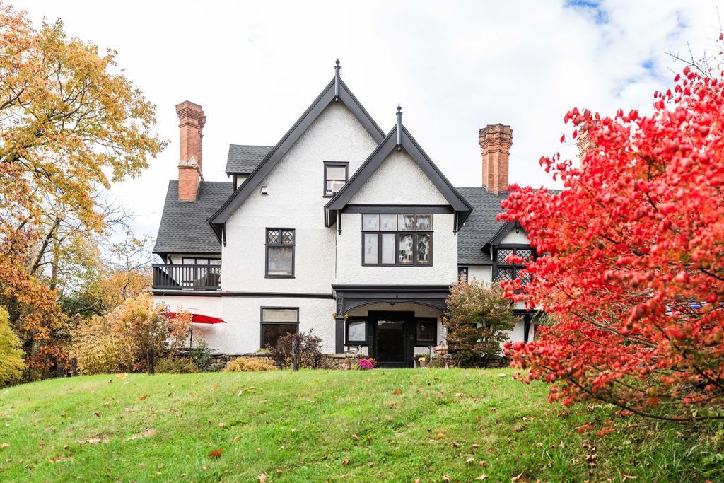 A large white house with red leaves in front of it.