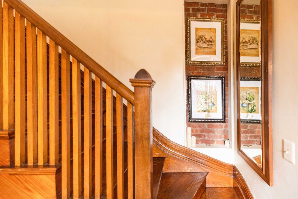 A wooden staircase with a wooden railing and a mirror on the wall.